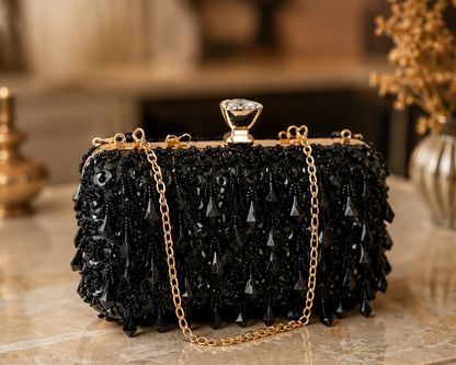 Femme portant une pochette noire ornée de cristaux avec chaîne dorée